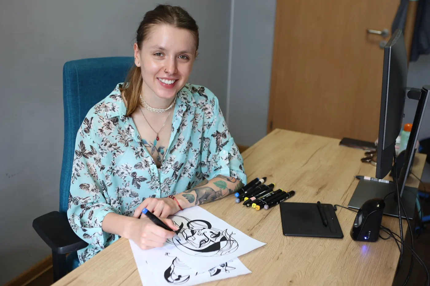 Marta Matczyńska uśmiechnięta przy biurku z rysunkami